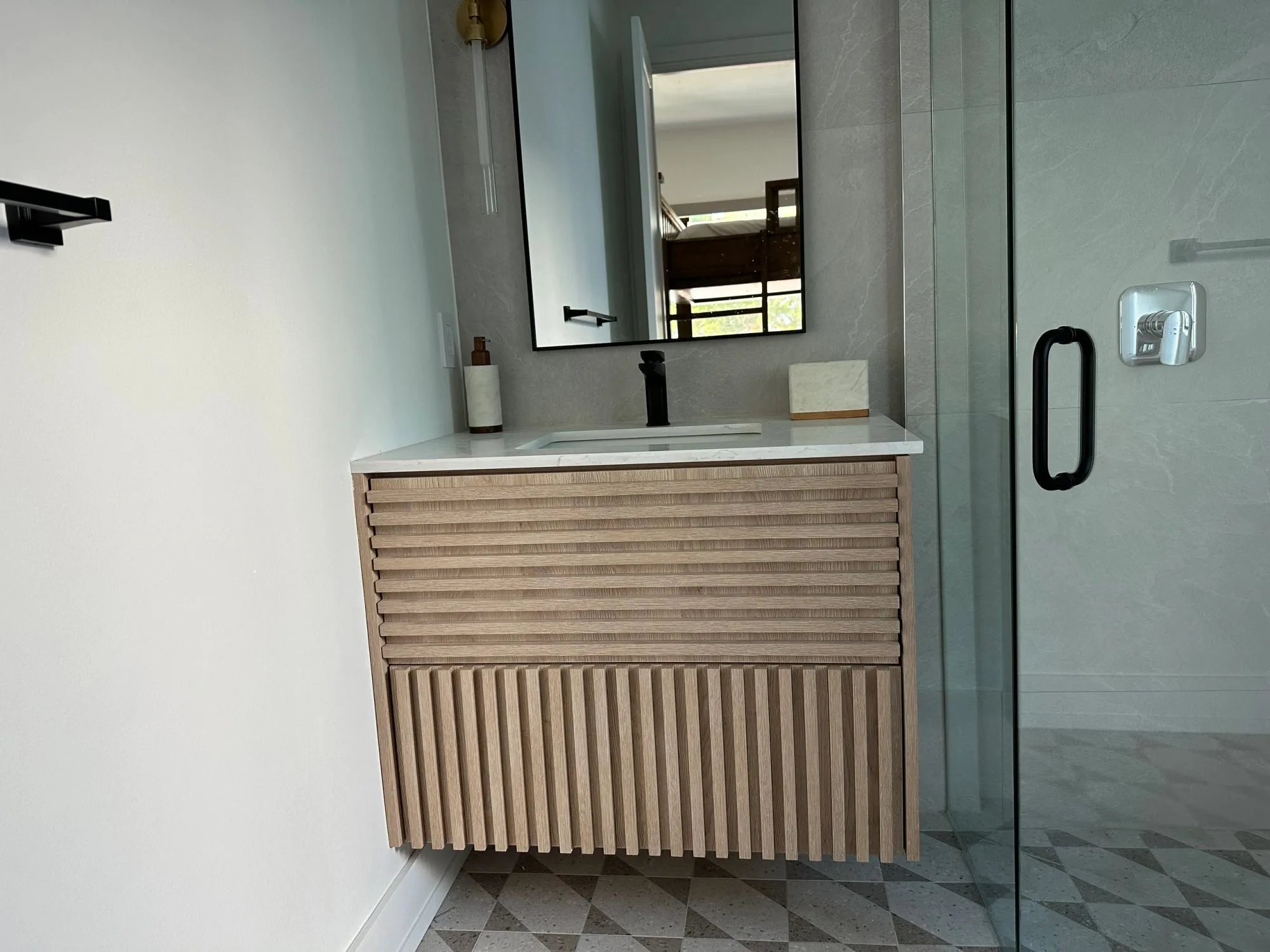 A fluted white oak floating vanity with a stone top