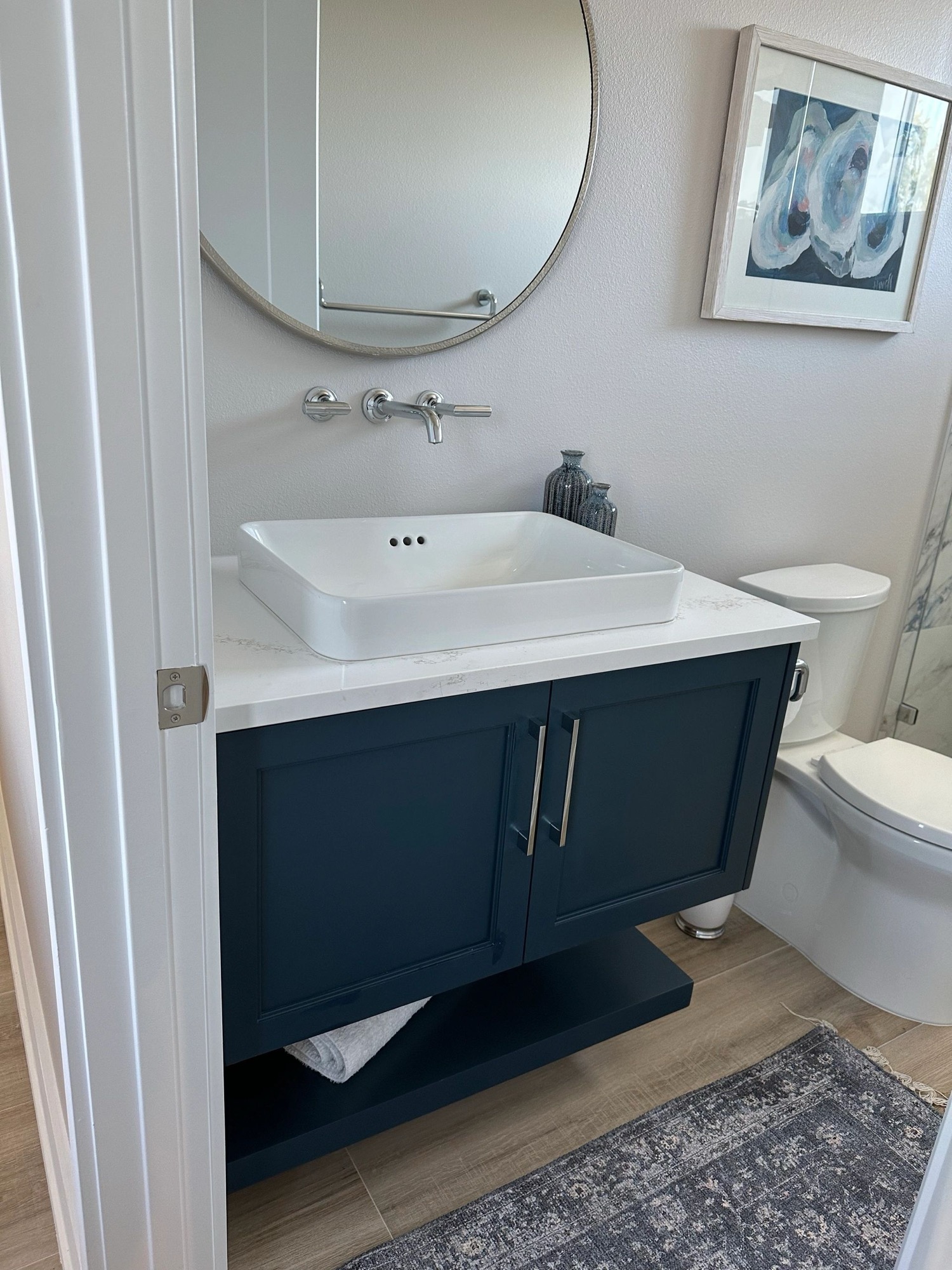A navy powder room vanity with a vessel sink
