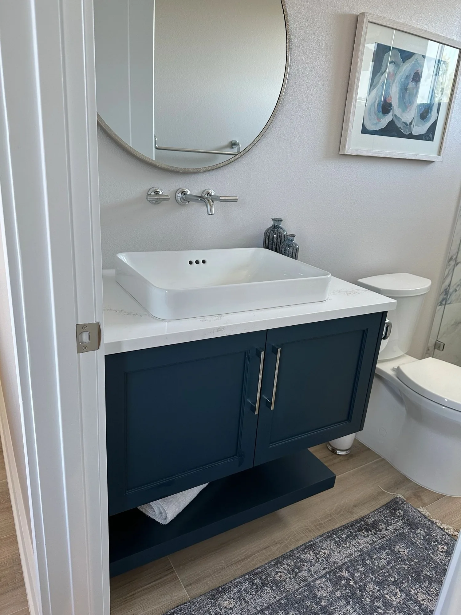 A navy powder room vanity with a vessel sink